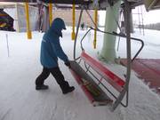 Il sedile viene spazzato dalla neve con una scopa all’ingresso